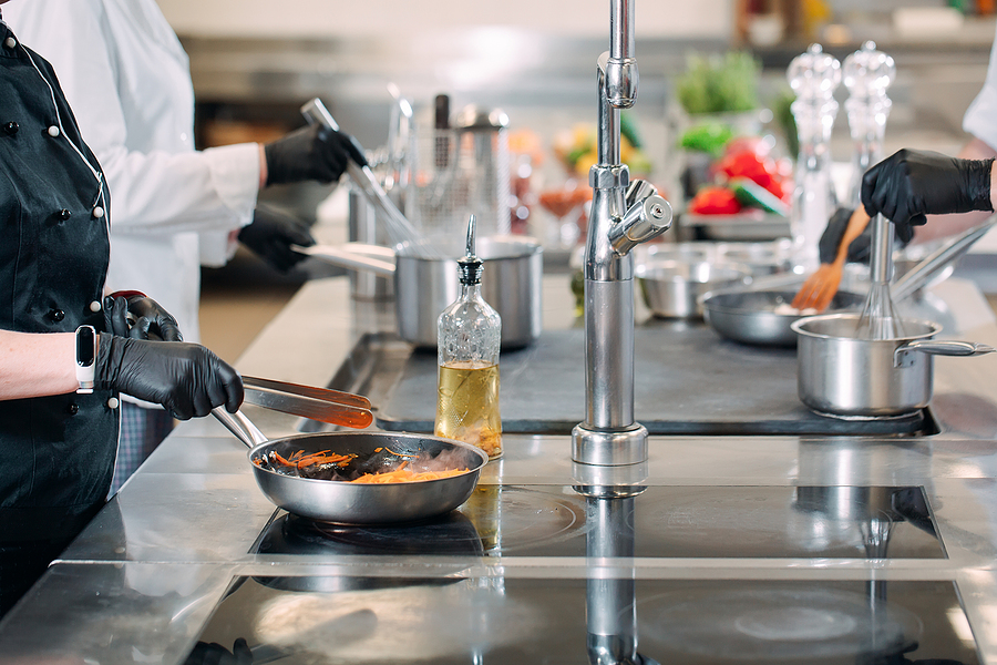 Cooks prepare meals on an electric stove in a professional kitchen in a restaurant.