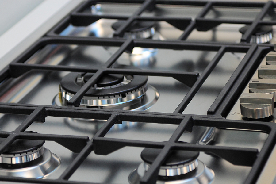 Close-up of a stainless steel gas cooktop with multiple burners and black cast iron grates.